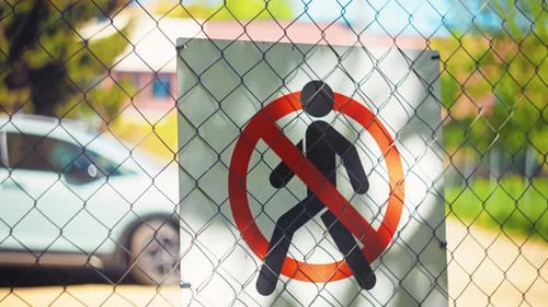 A Prominently Displayed No Pedestrian Access Sign is Positioned on a Fenced Area Beneath a Clear