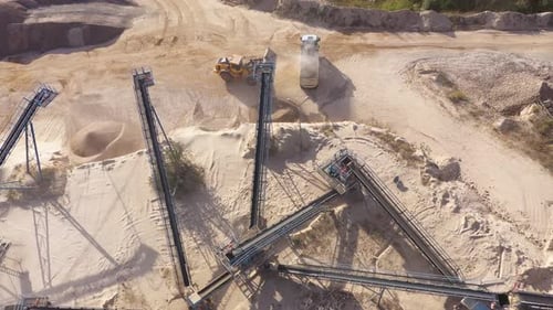 Aerial view of an excavator loading crushed stone into a dump truck in a crushed stone quarry