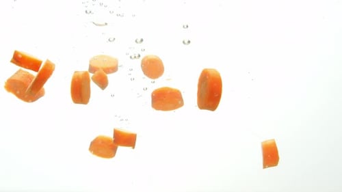Fresh pieces of carrot dropped into water, close up view