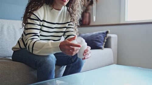 Woman Holding Pill Bottle on Sofa at Home