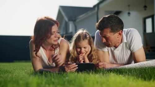 Family Together on Lawn with Tablet on Sunny Day
