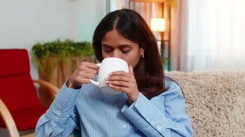 Woman Drinking From Mug on Cozy Couch