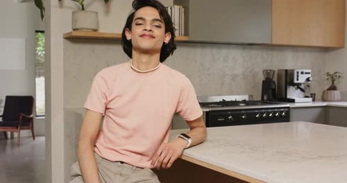 Homme adulte remarquant la caméra se transformant en sourire assis sur un comptoir en marbre montrant sa facilité