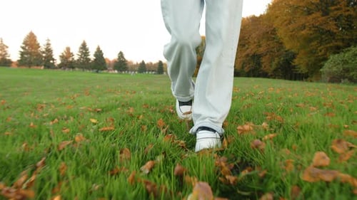 Closeup Shot of Female Legs Walking Along Grassy Meadow in City Park
