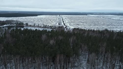 A Breathtaking Aerial View Depicting a Snowcovered Forest Alongside a Winding Road in a Serene