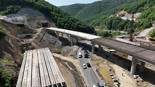 Aerial view of cranes and bridge foundation pillars on construction site of new highway road project