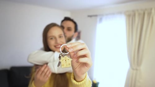 Excited Woman Displays Key While Cheers With Man for New Home