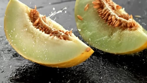 Melonenstücke fallen auf eine nasse Oberfläche, gefilmt mit einer Hochgeschwindigkeitskamera mit 1000 Bildern pro Sekunde