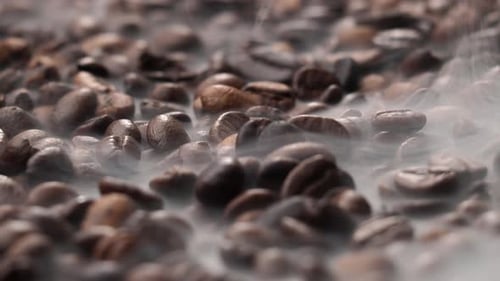 Roasted coffee beans. The smoke comes from fresh coffee seeds.