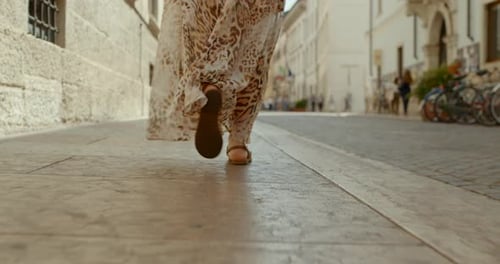 Female feet in sandals walk through ancient city center, tracking shot