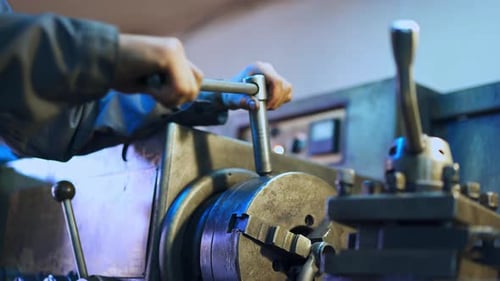 Hands of a turner applying lathe wrench. Man tuning turning lathe to work. Close up.