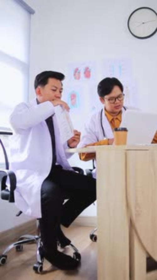 Serioused Doctors collaborating on patient diagnosis reviewing X-ray results together in clinic