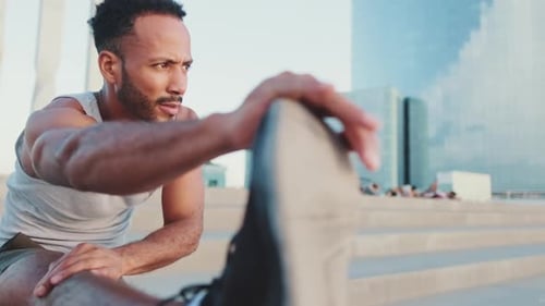 Close up, athlete doing warm-up, stretching legs before training while standing on the embankment