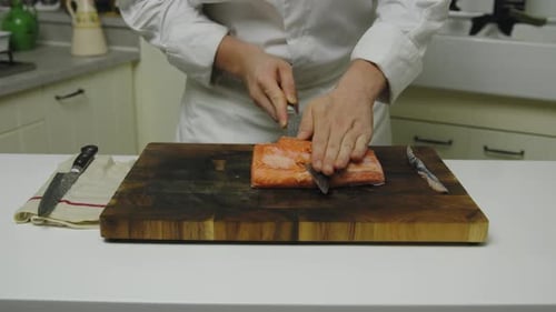 Starred Chef cutting fresh salmon fillet into slices on wooden board,close up