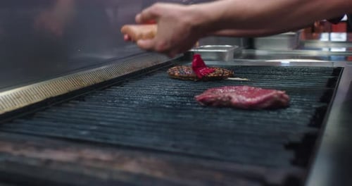 The cook is oiling the fresh meat and adding a new part of meat