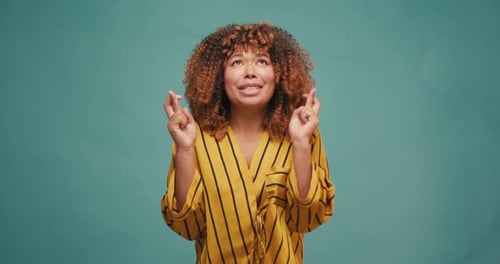 Woman Holding Fingers Crossed on Blue Background
