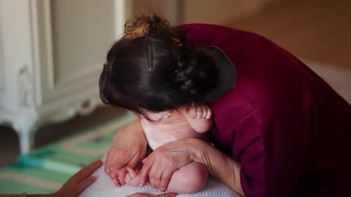 Caring Woman Holds Infant with Another Woman Nearby