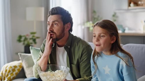 Father and Daughter Watching Scary Movie with Popcorn