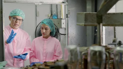 На заводе по производству напитков два инженера-механика обсуждают контроль качества с помощью цифрового планшета