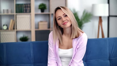 Smiling Blond Woman Sits on Couch Indoors