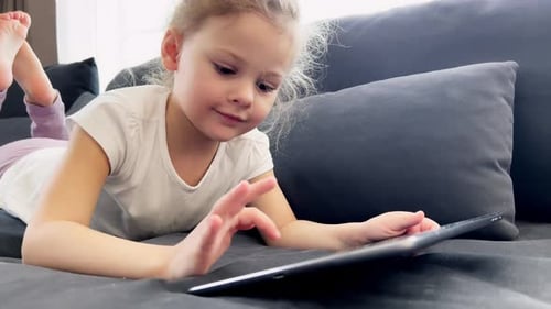 Young Child Lying on Couch Using Tablet