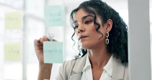 Young Woman Strategizes on Transparent Board in Office