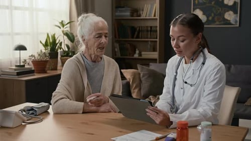 Arzt befragt ältere Patienten zu Gesundheitsproblemen und macht sich Notizen auf dem Tablet
