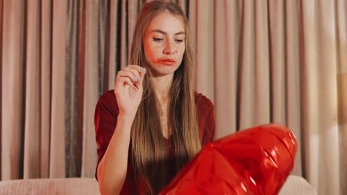 Woman popping a heart shaped balloon with needle