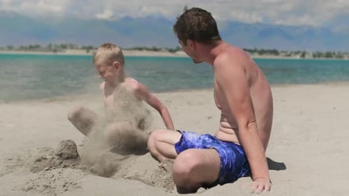 Father and Son Playing in the Sand on the Beach Family Travel and Vacation Concept Child with Dad