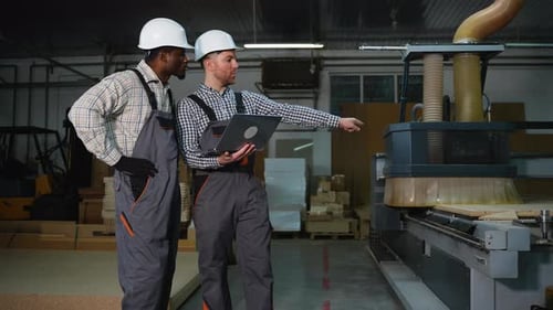 Two Engineers Discuss MDF Cutting on Laptop at Furniture Factory