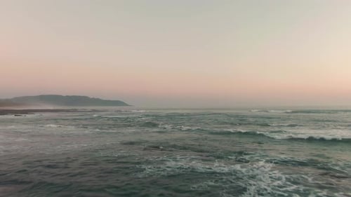 Aerial reveal flight of tide swell breaking on tropic Costa Rica beach in sunset