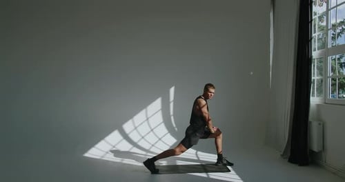 Young Athletic Man Training in a Bright Studio with Dramatic Shadows