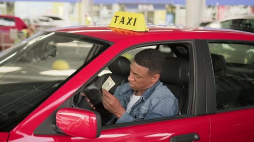 Taxi Driver Counting Cash in Red Car