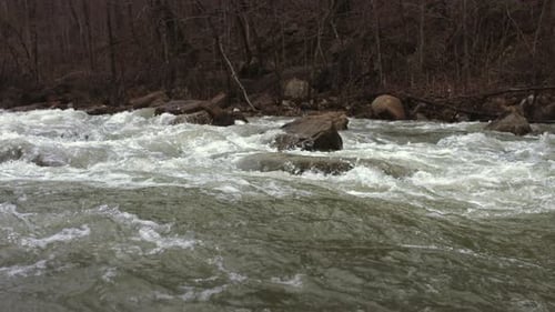 Superzeitlupenaufnahmen, die nach einem starken Regen über die Wildwasserschnellen eines Baches schwenken.