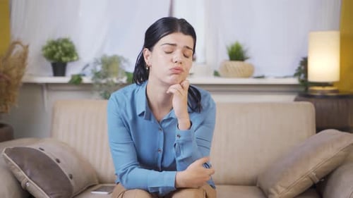 Pensive Woman Sitting on Couch at Home