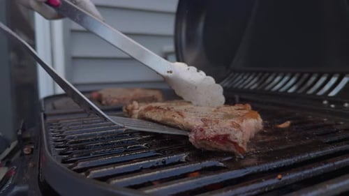 Meat Steaks Grilling and Flipping on Stove BBQ Grill Near the House Outdoor Party Food Top Down View