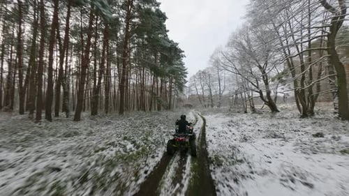 Offroad of atv riders speeding in middle of forest in winter season .FPV shot.