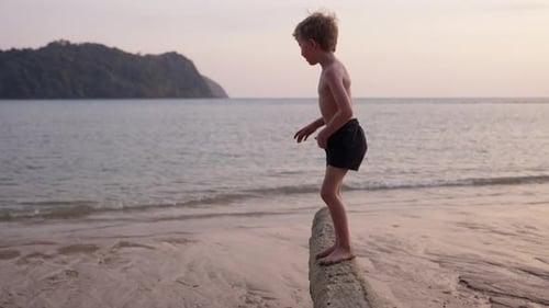 Boy On A Tree Trunk At The Beach