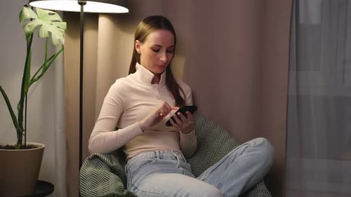 Young Woman Using Smartphone in Cozy Indoor Setting