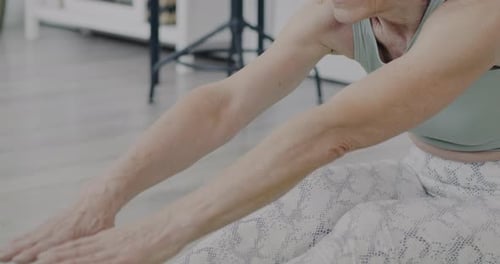 Senior Woman Stretching on Yoga Mat Indoors