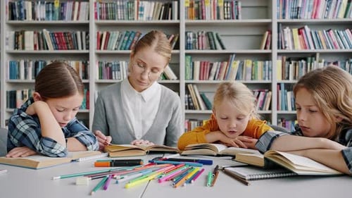 Lehrerin und Schülerinnen der Grundschule lesen Bücher