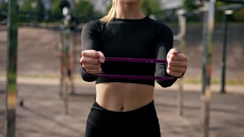 Close-up of a girl performing exercises with elastic bands to strengthen her arm muscles training