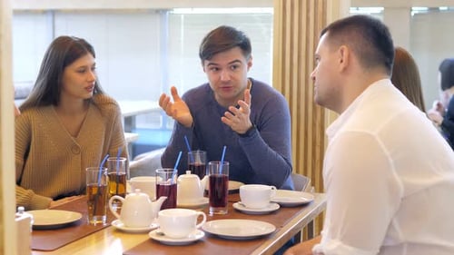 A Happy Group of Friends are Sitting at a Table in a Cozy Restaurant Laughing and Having Fun