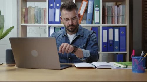 Attractive Focused Young Hipster Man Making Notes Using Laptop Office Computer Working on Project in