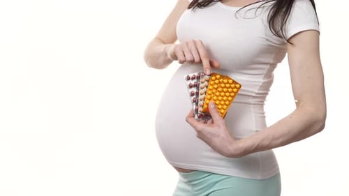 Pregnant Woman Holding Vitamins and Medicine