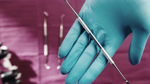 Gloved Hand Holds Shiny Dental Tools