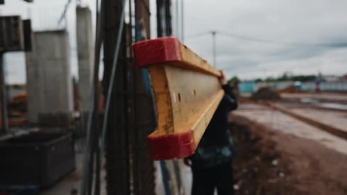 Worker Carrying Timber Beam for Formwork Assembly at Construction Site