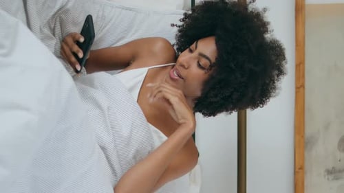 Awaking Girl Yawning Bed at Morning African Woman Reading Phone Laying Vertical