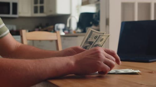 Man Handles Hundred Dollar Bills At Kitchen Table In Close Up