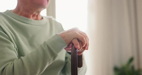 Nahaufnahme, Hände und älterer Mann mit einem Stock mit Behinderung zu Hause zur Unterstützung